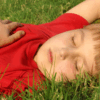 Child laying outdoors in spring, appearing tired — symbolizing the link between allergies and brain fog.