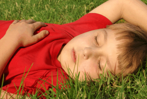 Child laying outdoors in spring, appearing tired — symbolizing the link between allergies and brain fog.