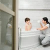 A mother and her young son are laughing together during bath time in a bright, clean bathroom. This image illustrates a happy home environment, underscoring the importance of mold prevention in high-humidity areas like bathrooms to keep them safe and healthy for children.