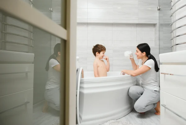 A mother and her young son are laughing together during bath time in a bright, clean bathroom. This image illustrates a happy home environment, underscoring the importance of mold prevention in high-humidity areas like bathrooms to keep them safe and healthy for children.